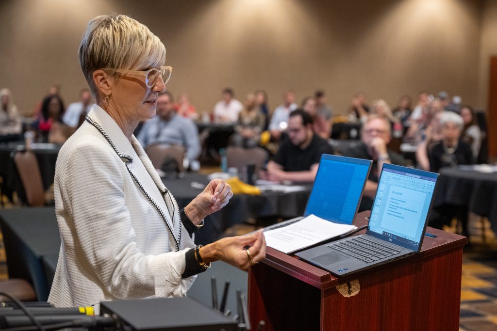 Woman standing behind podium speaking to audience